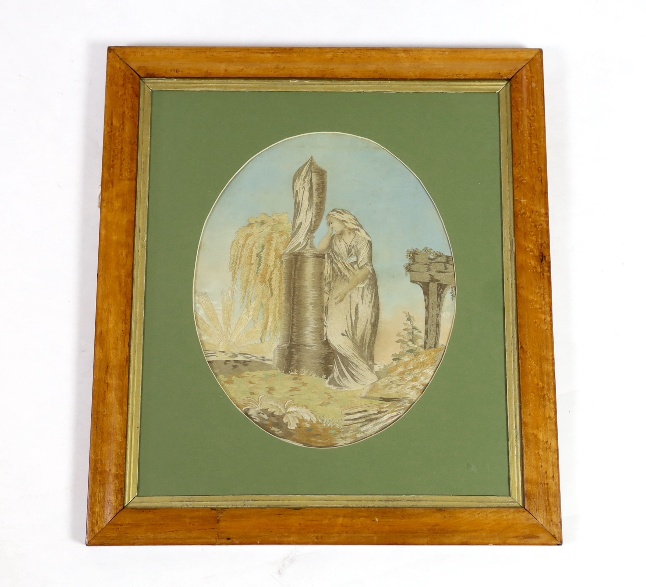 A Regency maple framed oval silk worked embroidery; a classical scene of young female figure by a garden urn. Worked mostly in stem stitch in subtle greys, browns and ochres, embroidery 33cm high